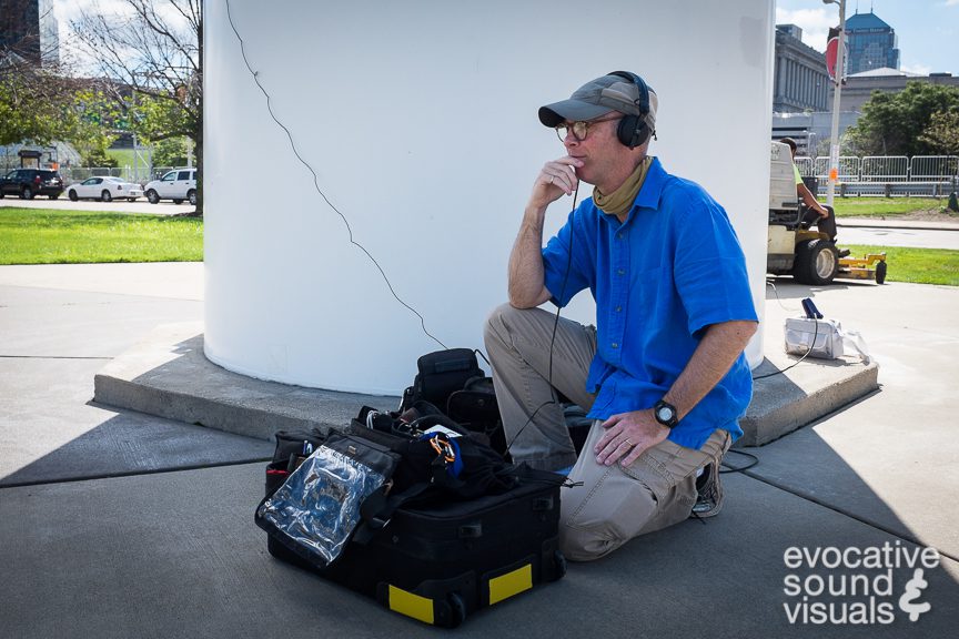 Richard Alan Hannon using contact microphones to record the Vestas V27 wind turbine as its 89-foot-diameter rotors cast a spinning shadow in front of the Great Lakes Science Center in Cleveland, Ohio August 18, 2016. Installed in 2006, the 146-foot tall turbine, capable of generating 225 kW of electricity (enough to power over 300 refrigerators) when wind speeds reach 31-mile per hour, needs a minimum 8-m.p.h. breeze to generate electricity, according to signage posted at the museum. Photo by Denise Porter