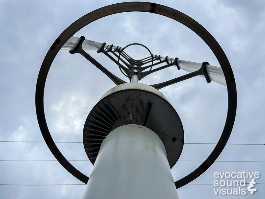 Recording the sound of a Windspire Energy Model 800080 vertical axis wind turbine, built in 2010, with a pair of contact microphones in Northfield, Ohio on January 5, 2022. The manufacturer states on the bottom of the unit that there are “no user serviceable parts inside,” which in this case is clearly too bad, as this unit is incredibly squeaky, like fingers raking across a chalkboard, and a bit wobbly as well. Photo by Richard Alan Hannon