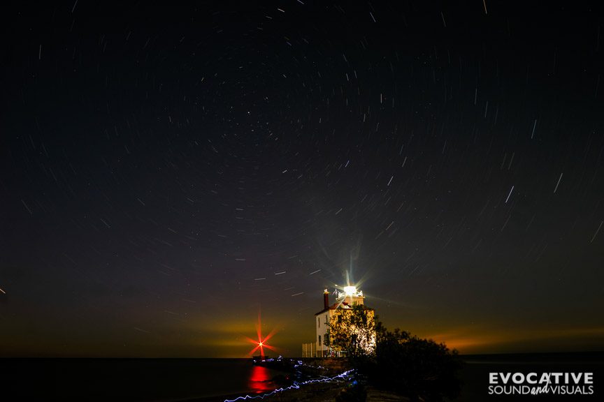 The 100-year-old Fairport Harbor West Breakwater Lighthouse shines well past sunset over Lake Erie at Headlands Beach State Park in Mentor, Ohio on Sunday, June 1, 2025. The 15-minute exposure causes the fisherman's headlamp to squiggle as he walks toward the lens. Light pollution from Canada can be seen as well. Photo by Richard Alan Hannon